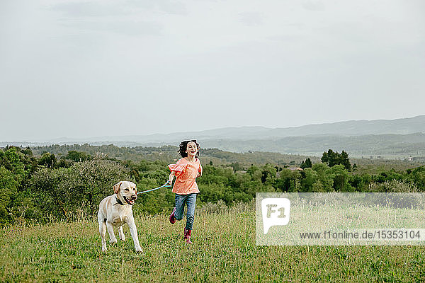 Girl running with labrador dog in scenic field landscape  Citta della Pieve  Umbria  Italy