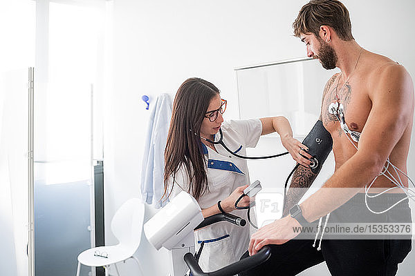 Krankenschwester führt EKG-Test am Patienten im Sprechzimmer durch