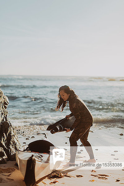 Frau setzt Flossen in Kajak am Strand  Big Sur  Kalifornien  Vereinigte Staaten