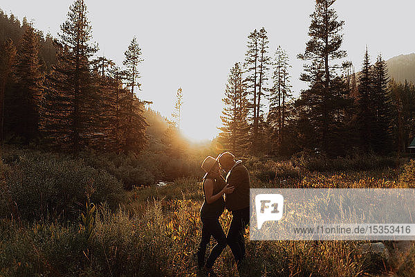Schwangere Paare im mittleren Erwachsenenalter stehen sich bei Sonnenuntergang in einem ländlichen Tal gegenüber  Mineral King  Kalifornien  USA