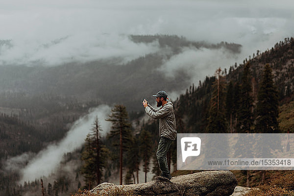 Wanderer beim Fotografieren der Ansicht des nebelverhangenen Tals  Yosemite National Park  Kalifornien  Vereinigte Staaten