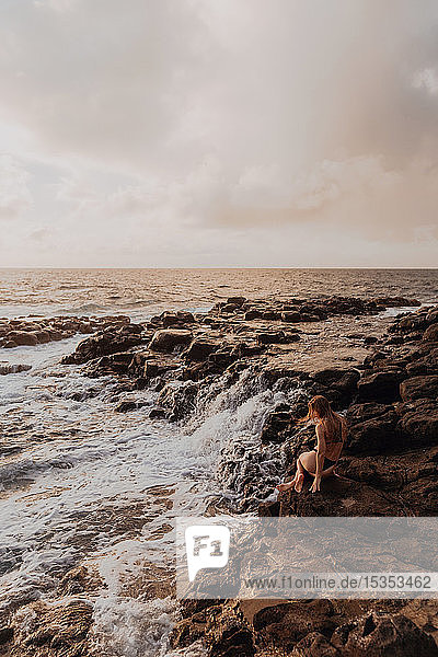 Frau sitzt auf Felsen am Meer  Princeville  Hawaii  USA