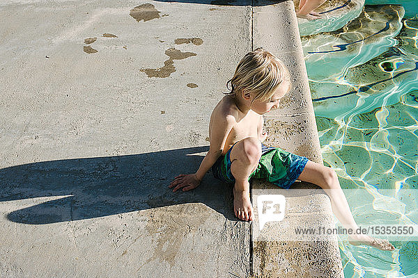 Junge am Schwimmbad sitzend