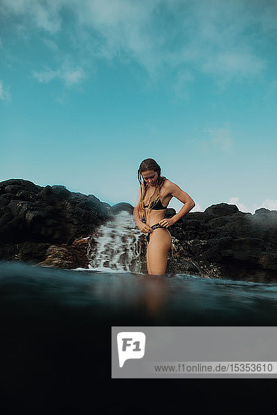 Woman standing in sea by rocks  Princeville  Hawaii  US