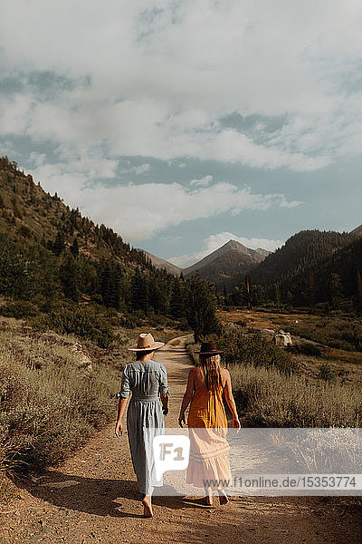 Zwei Frauen in Maxikleidern beim Spaziergang auf der ländlichen Talstrasse  Rückansicht  Mineral King  Kalifornien  USA