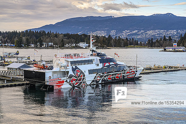 Ferry with indigenous artwork painted on the side moored at a waterfront; Vancouver BC Canada