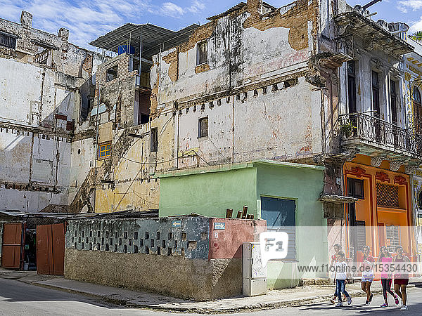 Fußgänger gehen auf der Straße an einem heruntergekommenen Gebäude vorbei; Havanna  Kuba