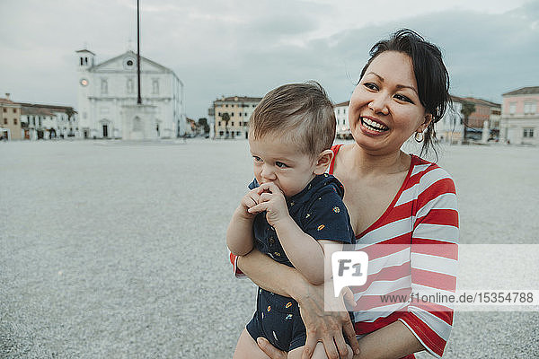 Eine Frau hält einen kleinen Jungen am Strand; Italien
