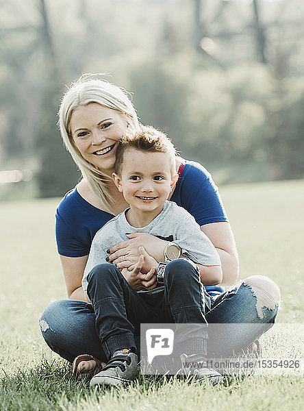 Porträt einer Mutter mit ihrem kleinen Sohn  die in einem Park im Gras sitzen; Edmonton  Alberta  Kanada