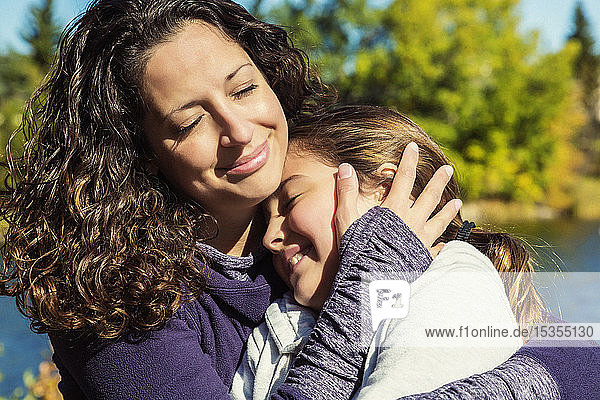 Eine Mutter umarmt ihre Tochter fest während eines Familienausflugs in einem Stadtpark an einem warmen Herbsttag; Edmonton  Alberta  Kanada