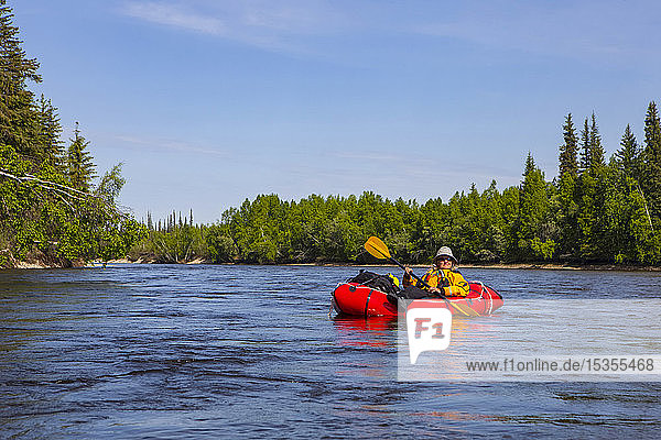 Rucksacktouristin entspannt sich auf einem sanften Abschnitt des Charley River  Yukonâ€ Charley Rivers National Preserve; Alaska  Vereinigte Staaten von Amerika