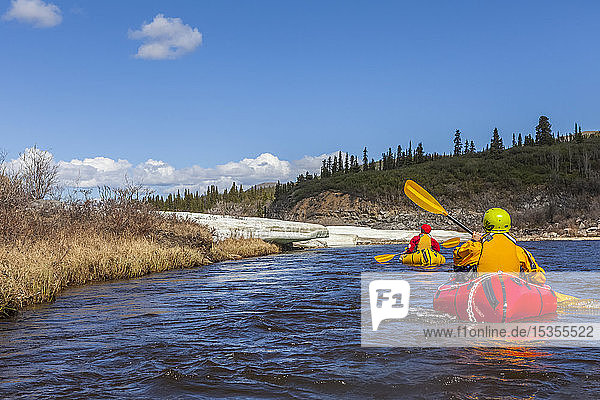 Female packrafters negotiating a tributary of the Charley River with aufeis in summer; Alaska  United States of America