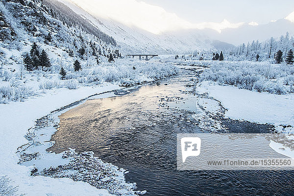 Fluss  der bei Sonnenaufgang durch eine verschneite Berglandschaft fließt; Alaska  Vereinigte Staaten von Amerika