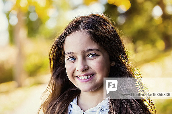 A young girl posing for the camera in a city park on a warm autumn day; Edmonton  Alberta  Canada