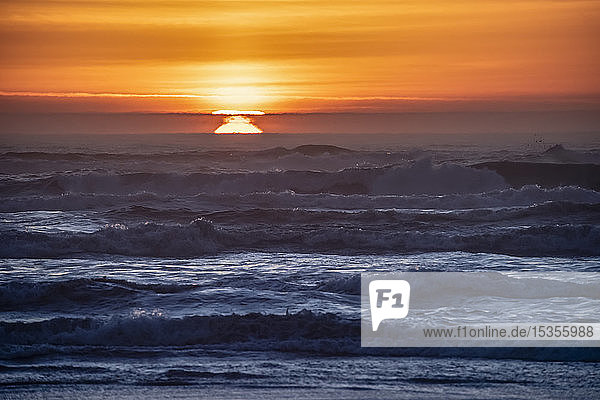 Sonnenuntergang über den Wellen am Cape Disappointment  Washington. Die atmosphärische Inversion bewirkt  dass die Sonne an mehreren Orten gleichzeitig erscheint. Dieser Effekt ist auch als Feta Morgana bekannt; Ilwaco  Washington  Vereinigte Staaten von Amerika