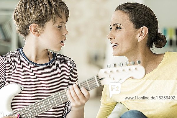 Mutter und Sohn musizieren zusammen  beide singen und Sohn spielt E-Gitarre  Nahaufnahme  Deutschland  Europa