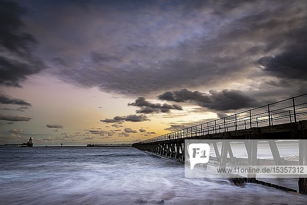 Bridge in the sea with dramatic clouds at sunset  harbour entrance  Newcastle upon Tyne  Northumberland  Great Britain