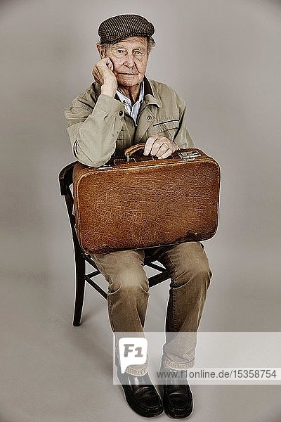 Senior sitzt mit altem Koffer auf einem Stuhl  Symbolbild Abschied  Sehnsucht  Studioaufnahme  Deutschland  Europa