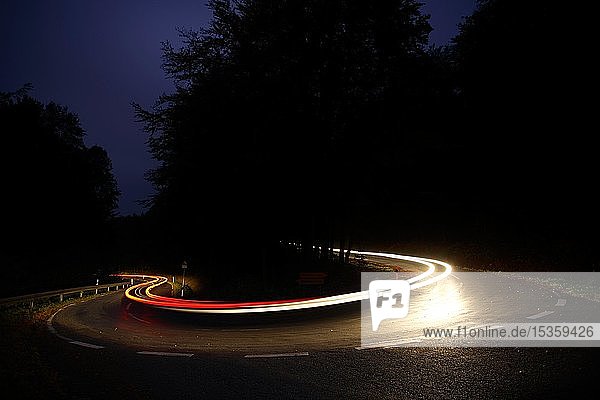 Autofahrt auf kurvenreicher Landstraße bei Nacht  weiße und rote LichtspurenHaarnadelkurve  Reinhardswald  Hessen  Deutschland  Europa