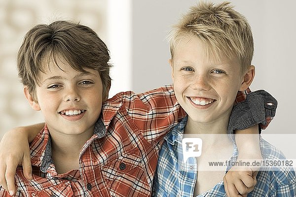 Zwei Jungen in karierten Hemden  Freunde  10 Jahre alt  schauen lächelnd in die Kamera und umarmen sich  Deutschland  Europa