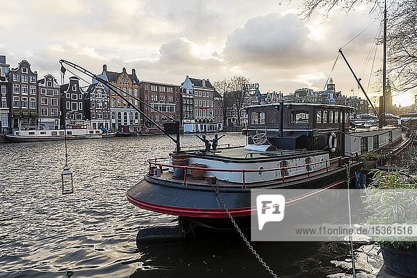 Blick über die Amstel im Abendlicht  Gracht mit Boot und historischen Häusern  Amsterdam  Nordholland  Niederlande
