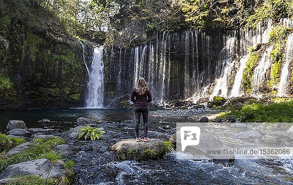 Junge Frau steht auf einem Stein in einem Fluss  Shiraito-Wasserfall  Präfektur Yamanashi  Japan  Asien