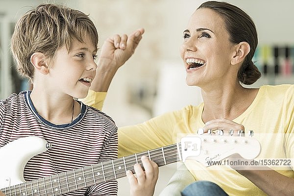 Mutter und Sohn musizieren zusammen  Mutter singt und Sohn spielt E-Gitarre  lachen  Portrait  Deutschland  Europa