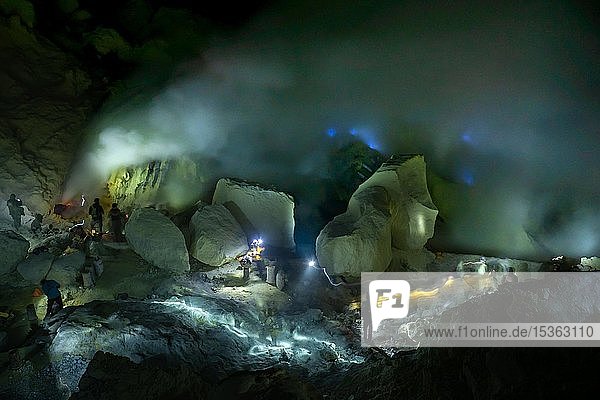 Arbeiter bei giftigem Schwefelabbau in Schwefelmine bei Nacht hinten blaues Feuer des Vulkans Ijen Ijen Java Indonesien Asien