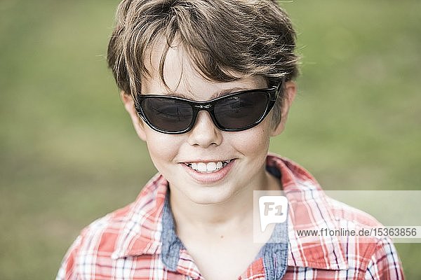 Junge  10 Jahre alt  mit Sonnenbrille und kariertem Hemd  lächelnd  Portrait  Deutschland  Europa