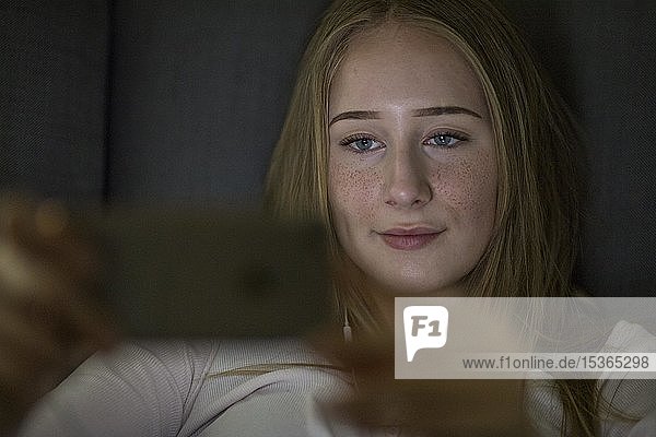 Teenager  girl  made-up with blue eyes playing on mobile phone  Germany  Europe
