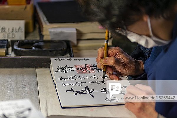 Frau schreibt japanische Schriftzeichen  Kalligraphie  Glücksbringer zu kaufen im Todaiji-Tempel  Japan  Nara  Japan  Asien