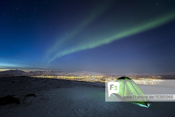 Green illuminated tent in the snow and aurora borealis above Fjellheisen  Tromsö  Norway  Europe