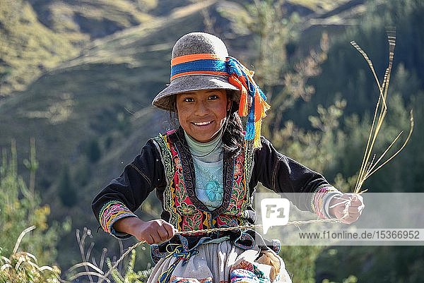Indio-Mädchen mit Hut lächelt und webt Pacha-Gras  nahe Cusco  Peru  Südamerika