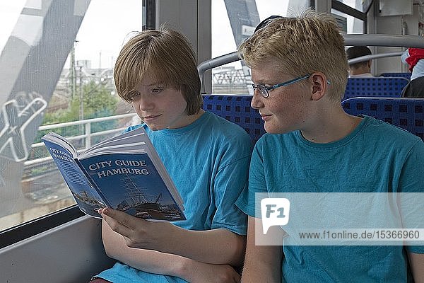 Junge Leute auf einer Sprachreise lesen im Zug einen englischen Reiseführer  Hamburg  Deutschland  Europa