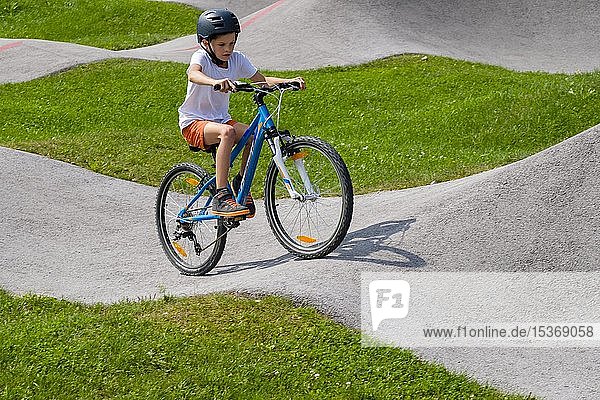 Child  boy  9 years old riding a mountain bike in a pump track  mountain bike trail  Viehhausen  Salzburg  Austria  Europe