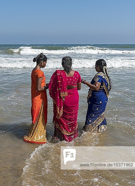 Drei Frauen im Sari-Kleid stehen im Meer an der Küste des Golfs von Bengalen  Mahabalipuram  Mamallapuram  Indien  Asien