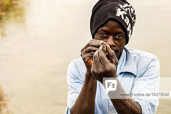 Afrikaner zeigt kleine gefangene Fische  Fluss Cuanavale  Provinz Cuando Cubango  Angola  Afrika