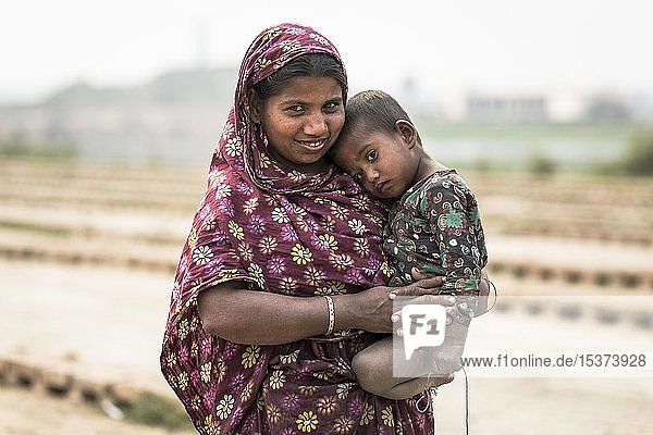 Lächelnde Frau mit einem kleinen Kind auf dem Arm  Dhaka  Bangladesch  Asien