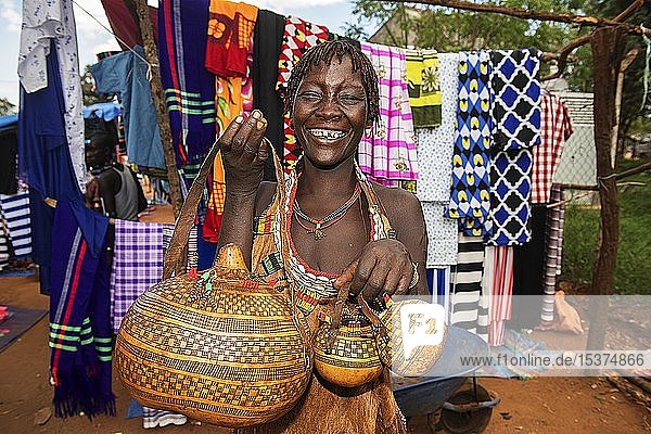 Lachende Frau der Volksgruppe der Hamer verkauft kunstvoll verzierte Kallebassen-Kürbisse Markt in Dimeka Unteres Omo-Tal Omo-Region Süd-Äthiopien Äthiopien Afrika