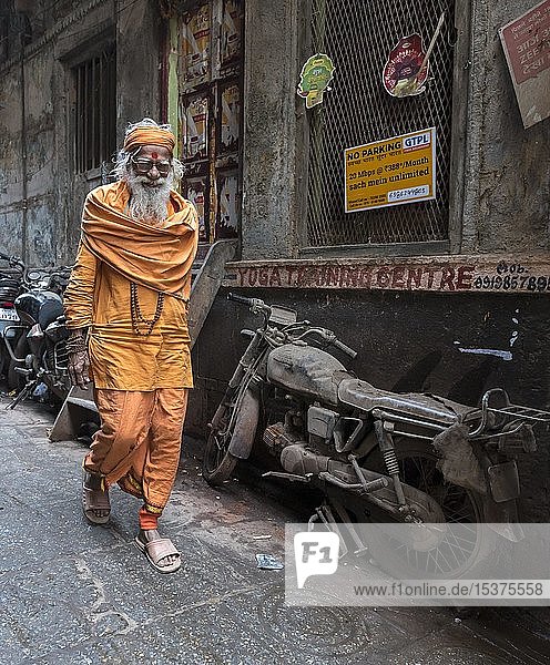 Hindu-Priester geht an einem verlassenen Motorrad in den engen Gassen vorbei  Altstadt von Varanasi  Uttar Pradesh  Indien  Asien