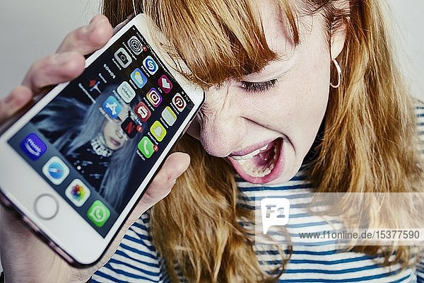 Mädchen  Teenager  rothaarig  hält verzweifelt ihren Kopf und schreit Smartphone  Studioaufnahme  Deutschland  Europa