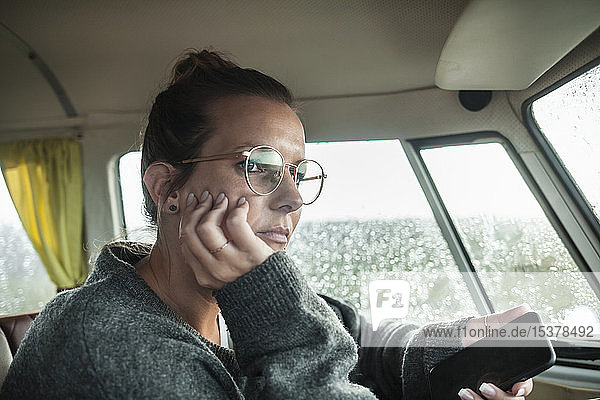 Woman with smartphone in a van looking sideways