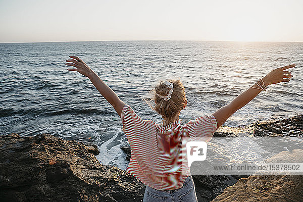 Rückansicht einer jungen Frau am Meer mit erhobenen Armen  Sunset Cliffs  San Diego  Kalifornien  USA