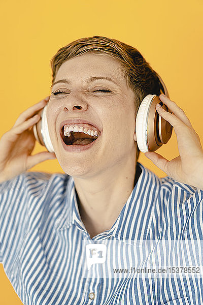 Porträt einer sorglosen  Musik hörenden Frau mit orangem Hintergrund