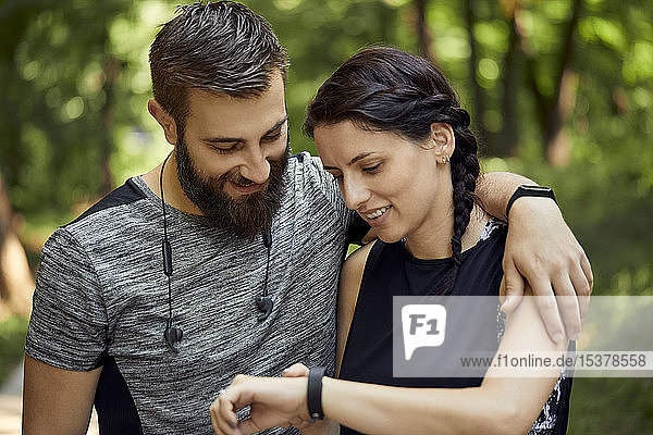 Happy sporty couple checking smartwatch