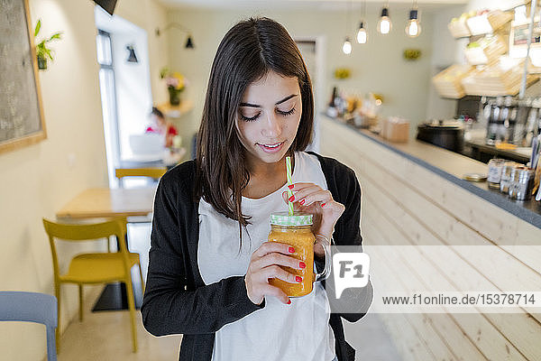 Junge Frau trinkt einen Smoothie in einem Café