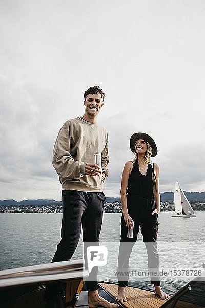 Glückliches junges Paar bei einem Drink während einer Bootsfahrt auf einem See