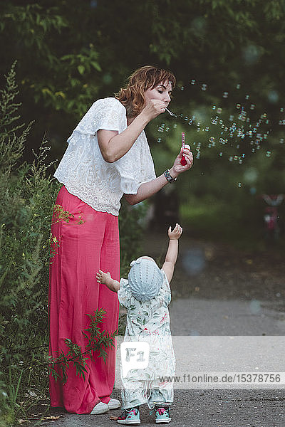 Mutter macht Seifenblasen für ihre kleine Tochter