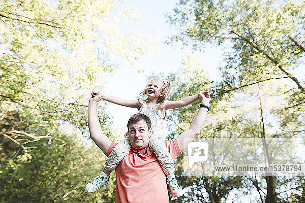 Father carrying happy daughter on his shoulders
