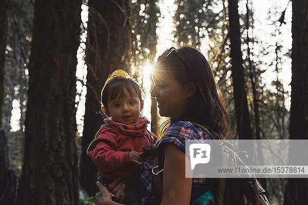 Mutter hält ein kleines Mädchen im Wald bei Sonnenuntergang im Sequoia-Nationalpark  Kalifornien  USA
